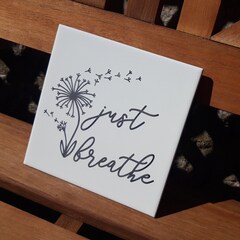 Just breathe sentiment etched on white ceramic tile.