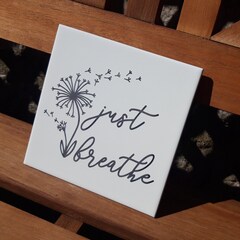 Just breathe sentiment etched on white ceramic tile.