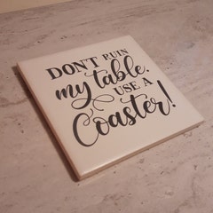 Laser etched ceramic tile. "Don't ruin my table. Use a Coaster."