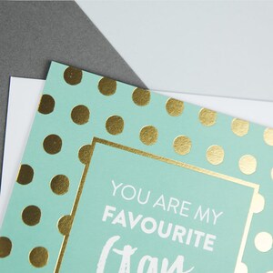 Pu&ograve; includere: Un biglietto di colore azzurro chiaro con pois dorati e un bordo bianco. Il testo all'interno del bordo recita "You are my favourite" con la parola "class" scritta in un grande carattere corsivo.