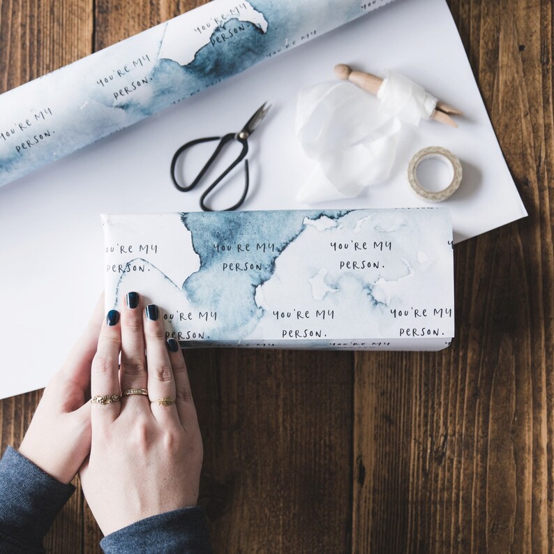 Puede incluir: Un papel de regalo blanco con dise&ntilde;os azules como de acuarela y el texto repetido "You're my person."