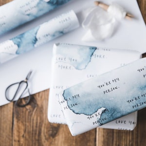 Puede incluir: Papel de regalo blanco con un dise&ntilde;o de acuarela azul y el texto "You're my person." repetido en todo el papel.