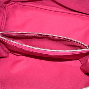 Puede incluir: Vista abierta de un neceser rosa brillante con un bolsillo con cremallera. El interior es de color rosa liso y el exterior presenta tela turquesa con lunares azules. La bolsa est&aacute; dise&ntilde;ada para guardar maquillaje y productos de belleza.