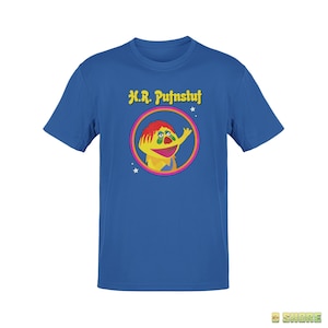 May include: A royal blue t-shirt with a yellow, red, and green cartoon character in a circle with the text "H.R. Pufnstuf" above the circle.