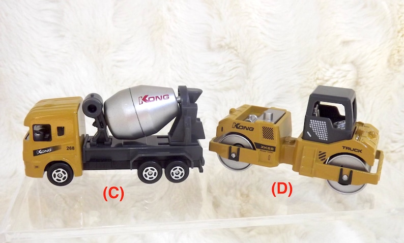 K&ouml;nnte beinhalten: Zwei Spielzeug-Baumaschinen, ein gelber Betonmischer-LKW mit einer silbernen Trommel und ein gelber Walzen-LKW mit schwarzen Details. Beide LKWs haben den Schriftzug "KONG" aufgedruckt.