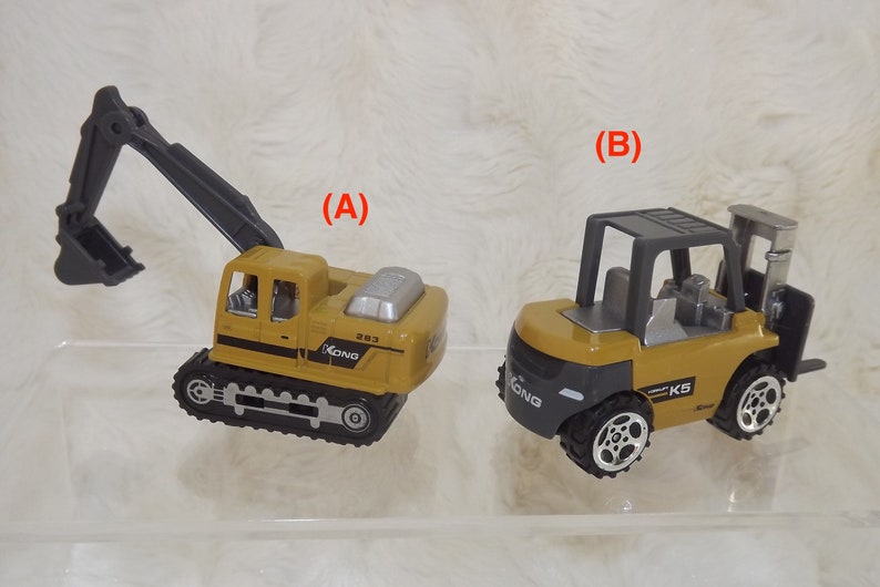 K&ouml;nnte beinhalten: Zwei Spielzeug-Baumaschinen, ein gelber Bagger mit einem schwarzen Arm und ein gelber Gabelstapler mit einer grauen Kabine. Beide Fahrzeuge haben schwarze Reifen und den Text "XONG" an der Seite.
