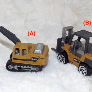 K&ouml;nnte beinhalten: Zwei Spielzeug-Baumaschinen, ein gelber Bagger mit einem schwarzen Arm und ein gelber Gabelstapler mit einem schwarzen Rahmen. Beide Fahrzeuge haben schwarze R&auml;der und sind mit dem Wort "Kong" beschriftet.