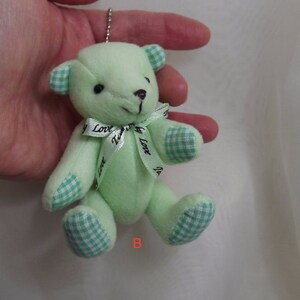 May include: A small green plush teddy bear with a white and green checkered pattern on its paws and ears. The bear has a green ribbon with the words "My Love" printed on it.