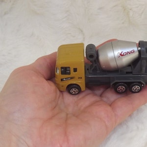 K&ouml;nnte beinhalten: Ein gelber Spielzeug-Betonmischer mit einem silbernen rotierenden Trommel. Der LKW hat den Schriftzug "KONG" auf der Seite der Trommel.