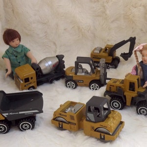 K&ouml;nnte beinhalten: Ein Set Spielzeug-Baufahrzeuge, darunter ein Betonmischer, ein Gabelstapler, ein Bulldozer, ein Kipplaster und eine Stra&szlig;enwalze. Die Fahrzeuge sind gelb und schwarz und haben den Schriftzug "KONG" aufgedruckt.