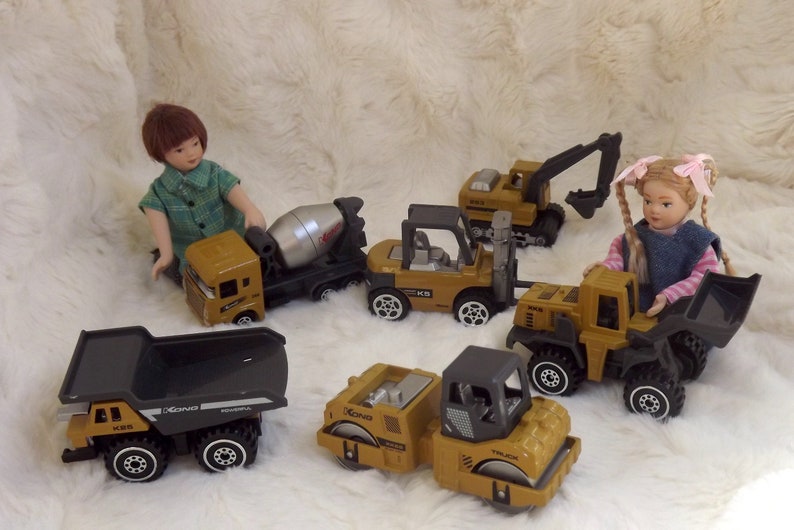 K&ouml;nnte beinhalten: Ein Set Spielzeug-Baufahrzeuge, darunter ein Betonmischer, ein Gabelstapler, ein Bulldozer, ein Kipplaster und eine Stra&szlig;enwalze. Die Fahrzeuge sind gelb und schwarz und haben den Schriftzug "KONG" aufgedruckt.
