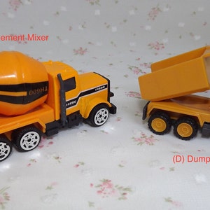 May include: Two toy construction trucks, a yellow cement mixer truck with black stripes and a yellow dump truck with a raised bed. Both trucks have black wheels.