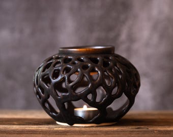 May include: Black ceramic oil burner with a delicate, intricate design resembling a coral reef. A small tea light candle sits inside the burner.