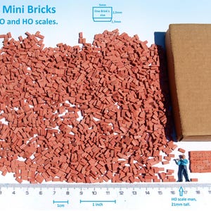 Peut inclure: Une grande quantité de petites pièces en forme de briques rouges, idéales pour la construction de modèles. Les briques sont réparties sur une surface blanche avec une règle pour l'échelle. L'image montre également une boîte en carton marron avec le texte "HAARON 88" imprimé sur le côté. Le texte "2000+ Mini Bricks best for O and HO scales." est visible en haut de l'image.