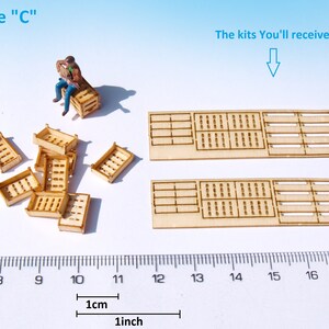 May include: A set of wooden crate kits for model building. The kits include two large crates and several smaller crates. The crates are made of unfinished wood and have a grid pattern. The kits are shown next to a ruler with measurements in inches and centimeters.