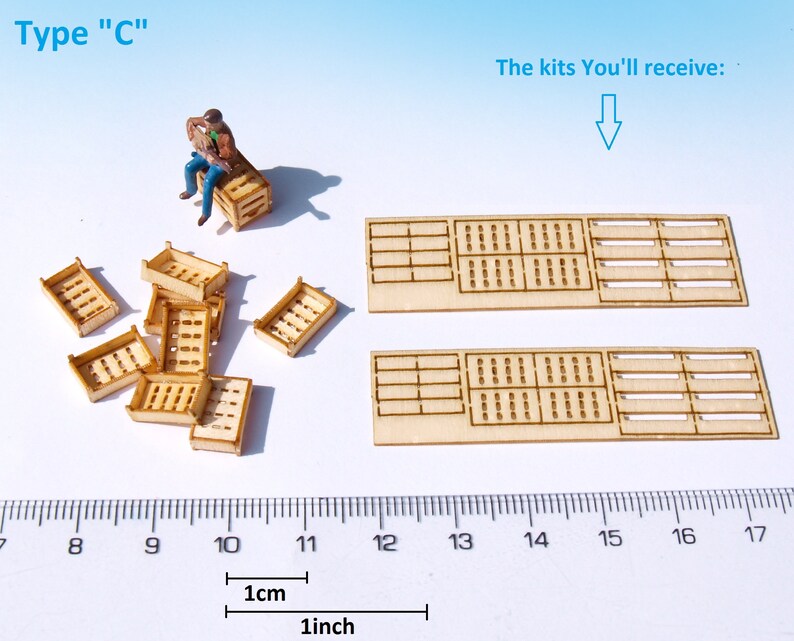 May include: A set of wooden crate kits for model building. The kits include two large crates and several smaller crates. The crates are made of unfinished wood and have a grid pattern. The kits are shown next to a ruler with measurements in inches and centimeters.
