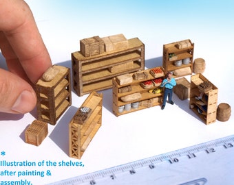 May include: A set of miniature wooden shelves, painted and assembled, with a small figure standing in front of one of the shelves. The shelves are arranged on a white surface with a ruler in the background.