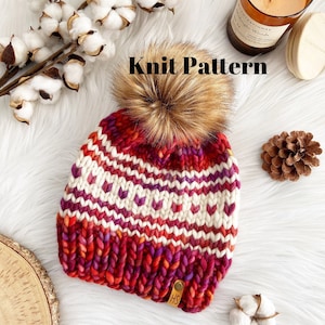 Puede incluir: Patrón de punto para un gorro rojo, blanco y morado con un pompón de piel sintética. El gorro tiene un patrón geométrico y una etiqueta de cuero con las iniciales "HS".