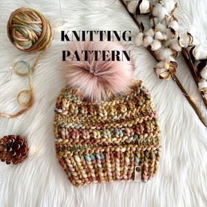 Puede incluir: Patrón de tejido para un gorro colorido con un pompón esponjoso. El gorro está hecho con un hilo grueso en tonos de rosa, marrón, beige y azul. El patrón está escrito "Knitting Pattern" sobre un fondo blanco.