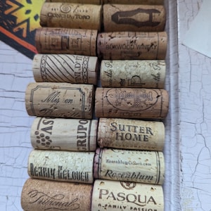 May include: A collection of wine corks with various labels, including "Handsome Devil", "Chateau St Jean", "Concha y Toro", "The Boxwood Winery", "Sutter Home", "Rosenblum", and "Pasqua".
