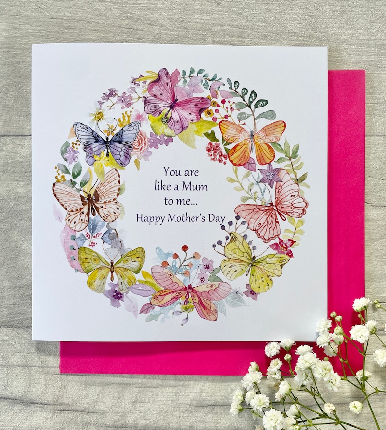 May include: A white card with a watercolor illustration of a wreath of butterflies and flowers. The text on the card reads "You are like a Mum to me... Happy Mother's Day."