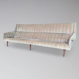 May include: A mid-century modern sofa with a striped pattern in shades of beige, red, and blue. The sofa has a high back, armrests, and wooden legs. The overall design is vintage and stylish.