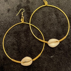 Brass and cowrie shell hoop earrings.