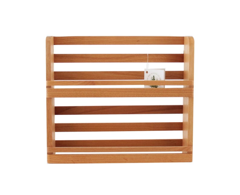 May include: A two-tiered wooden shelf unit with a natural wood finish. The shelf is designed for wall mounting and has a simple, rustic style.