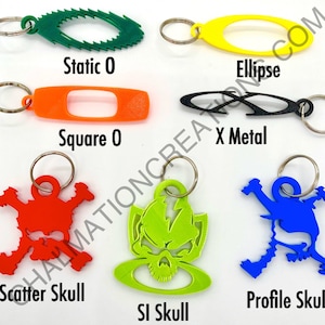 May include: A set of 10 keychains featuring different designs, including a skull, an X, a square, an ellipse, and a static O. The keychains are made of different materials, including metal and plastic, and are available in a variety of colors, including red, green, blue, black, and yellow.