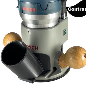 May include: A blue and gray Bosch router with a black dust collection tube and two wooden handles. The router has a digital display and the text "Bosch" is visible on the side.