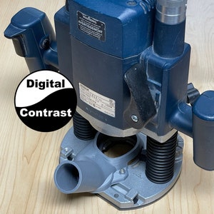 May include: A blue Bosch 1371-613-254 router with a gray dust collection port. The router has a black power cord and a black and white label that says "WARNING" and "AVERTISSEMENT".