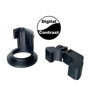 K&ouml;nnte beinhalten: Zwei schwarze Kunststoff-Objektivadapter f&uuml;r Kameras. Einer ist ein runder Adapter mit einem Gewindeloch und einem Sockel. Der andere ist ein Klemmadapter mit einem Gewindeloch. Der Text "Digital Contrast" ist auf einem schwarz-wei&szlig;en Kreis gedruckt.