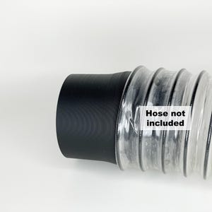 May include: Close-up of a black and clear flexible hose connector. The connector has a black rubber end and a clear plastic corrugated section. The text "Hose not included" is printed on the clear section.