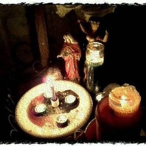 May include: A dark, dimly lit scene with a wooden table and a small, round, white plate with four lit candles. The plate is surrounded by a dark, textured surface. There is a glass jar with a lid and a red and gold figure in the background.