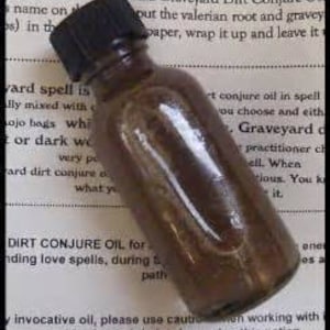 May include: A small, brown glass bottle with a black cap. The bottle is filled with a dark liquid. The label on the bottle reads "Dirt Conjure Oil for binding love spells, during...