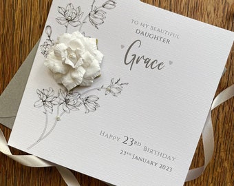 Puede incluir: Una tarjeta blanca con un diseño floral en blanco y negro y una flor 3D blanca. La tarjeta dice "To my beautiful daughter Grace" y "Happy 23rd Birthday 23rd January 2023".