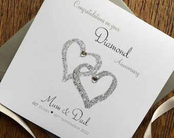 May include: A white card with silver glitter hearts and the text "Congratulations on your Diamond Anniversary Mum & Dad 60 YEARS 10TH SEPTEMBER 2022".