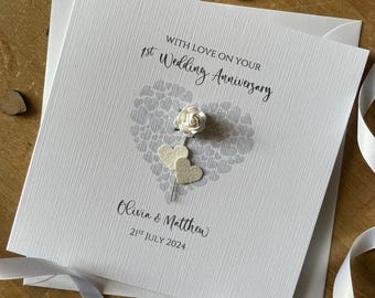 May include: A white card with a gray heart made of smaller hearts. The card says "With love on your 1st Wedding Anniversary" and "Olivia & Matthew 21st July 2024".