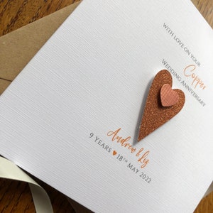 May include: A white card with a copper glitter heart and the text "WITH LOVE ON YOUR Copper WEDDING ANNIVERSARY 9 YEARS 18TH MAY 2022 Andrew & Liz"