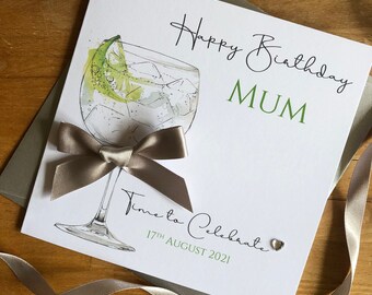 May include: A white card with a green and white illustration of a gin and tonic with a lime wedge. The card says "Happy Birthday Mum" in green and black script. The card also says "Time to Celebrate" in black script with the date "17th August 2021" below. A small silver heart is in the corner.