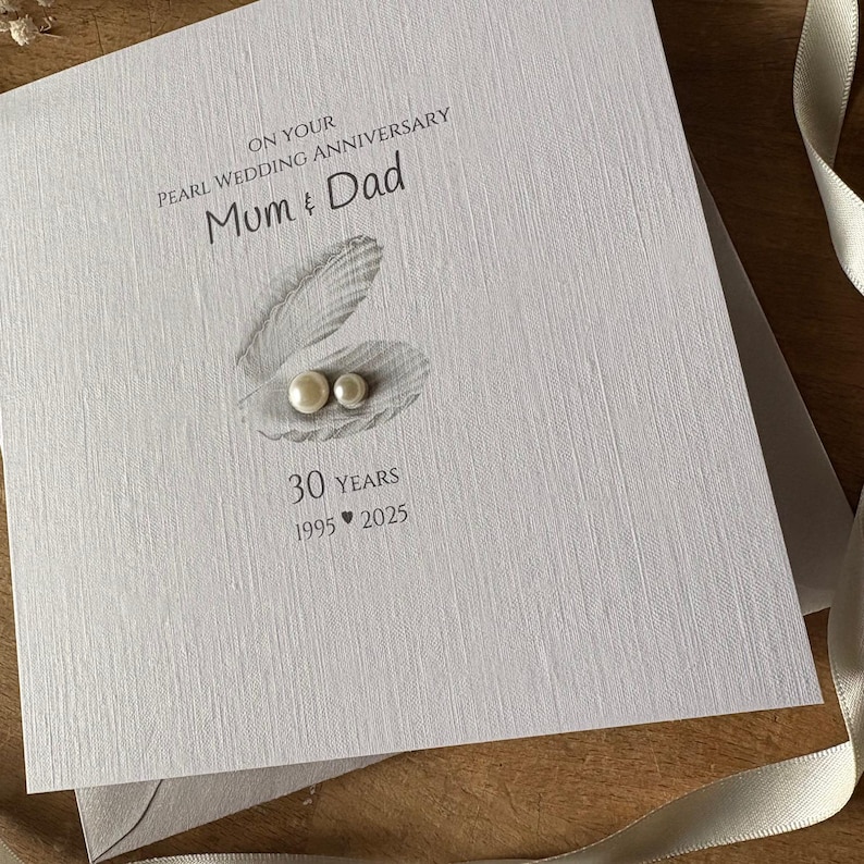 May include: A white Pearl Wedding Anniversary card with the text "Mum & Dad" and "30 Years 1995-2025". The card features a pearl design with two pearls inside a shell.