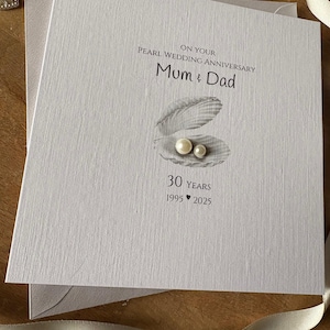 May include: A light gray Pearl Wedding Anniversary card with the text "On Your Pearl Wedding Anniversary Mum & Dad". The card features an illustration of a shell with two pearls and the text "30 YEARS 1995 2025".