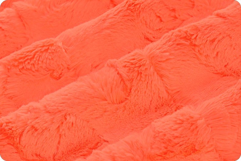 May include: Close-up of a bright orange fluffy fabric with a soft, plush texture.