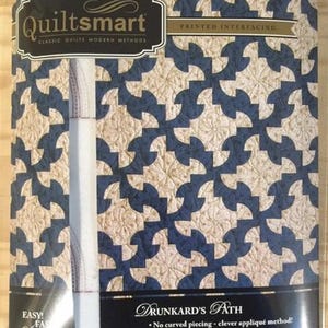 May include: A package of QuiltSmart printed interfacing for the Drunkard's Path quilt pattern. The package features a blue and beige geometric design. Text on the package includes "Classic Quilts Modern Methods" and "Easy! Fast! Make!"