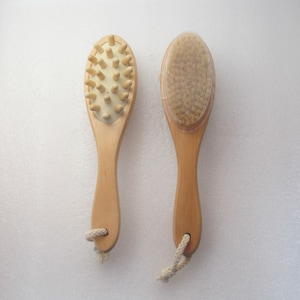 Op de afbeelding: Twee houten lichaamsborstels met natuurlijke borstels. Eén borstel heeft een getextureerd oppervlak en de andere heeft een zachte borstel. Beide borstels hebben een touwhandvat.