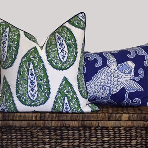 May include: Two decorative throw pillows, one with a white background and green paisley pattern, the other with a blue background and a white fish design.