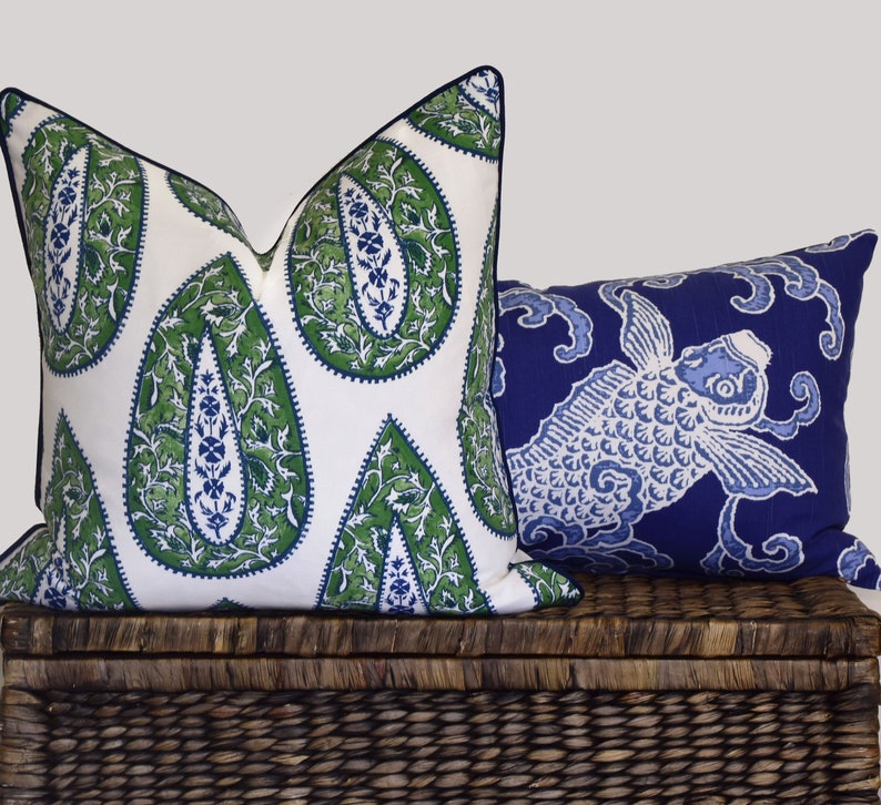 May include: Two decorative throw pillows, one with a white background and green paisley pattern, the other with a blue background and a white fish design.