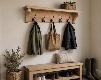 May include: A light wood wall-mounted coat rack with five dark metal hooks, featuring a top shelf holding a woven basket. Below, a matching light wood bench with a lower storage shelf holds shoes, a striped pillow, and a tote bag.