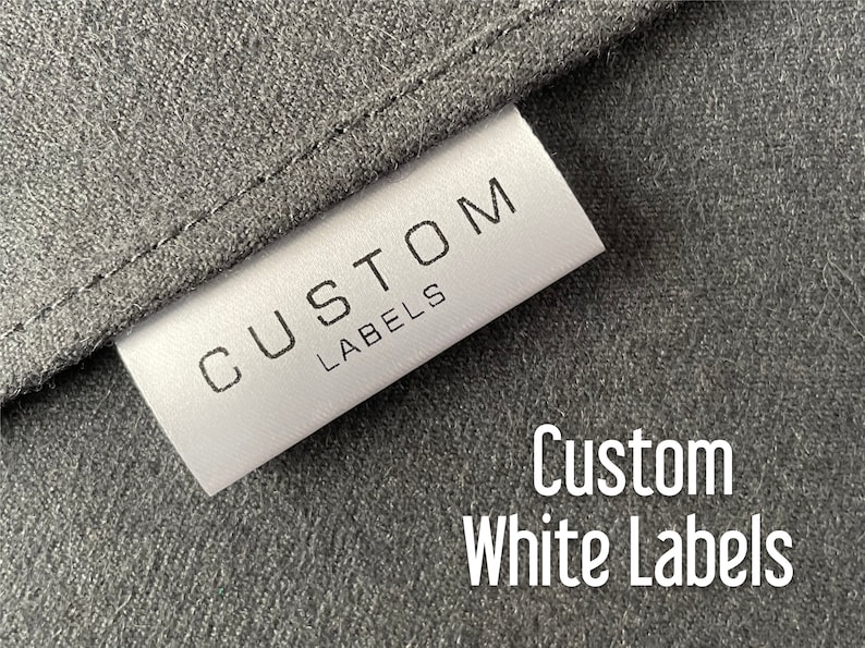 May include: A white label with the text "CUSTOM LABELS" printed in black. The label is attached to a dark gray fabric.
