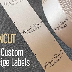 May include: A roll of beige satin ribbon labels with the text "Abigail Roberts - HANDMADE" printed in black.